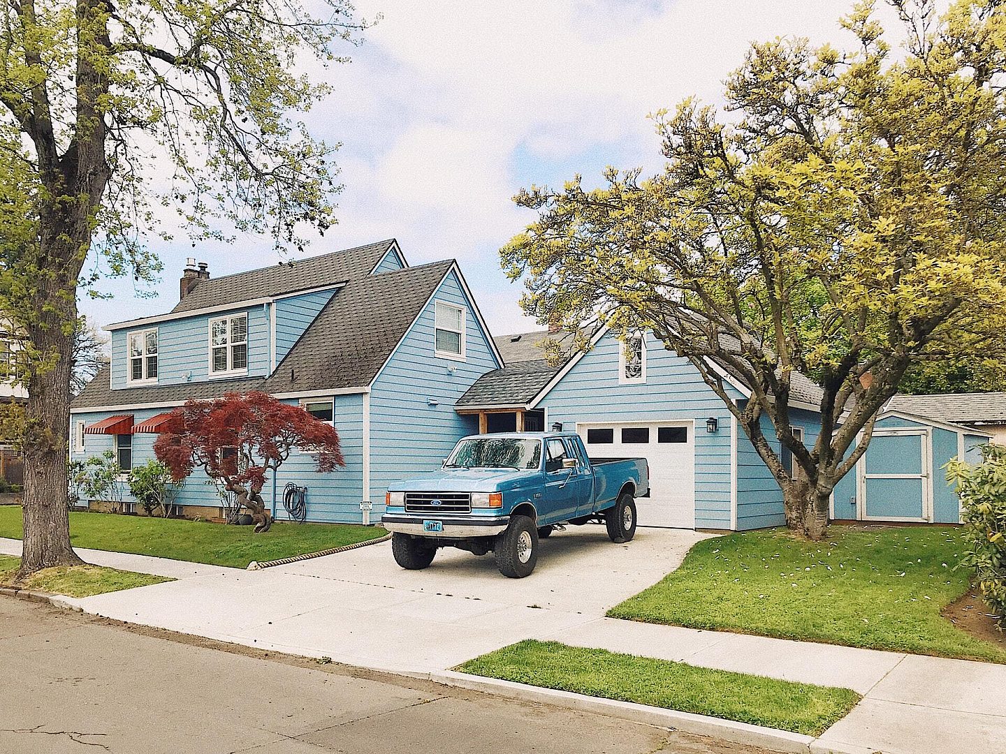 Painted Blue House with Blue Truck Sitting in Driveway